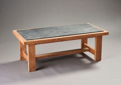 une table en bois avec un plateau en ardoise sur fond gris