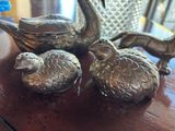 three silver birds sitting on a table next to a vase