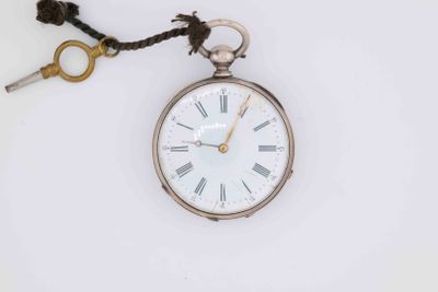 a silver pocket watch with a key attached to it