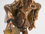 bronze statue of a man holding a book and a bag