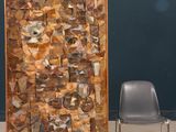 a chair sitting next to a large piece of art on the floor
