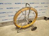 a yellow hose on a cart in front of a wall