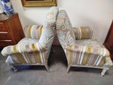 pair of striped upholstered chairs in a room with a painting on the wall