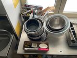 des casseroles et des poêles posées sur un plan de travail de cuisine, avec une fenêtre en arrière-plan