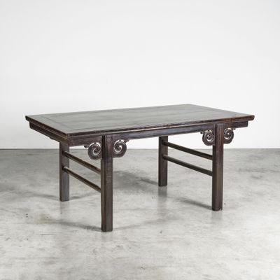 une vieille table avec un plateau en bois posée sur un sol en béton