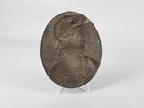 an image of a bronze plate with a woman ' s face on it