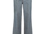 Cette femme porte un pantalon gris et une chemise blanche.