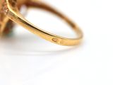 an image of a close up of a gold ring with a green stone
