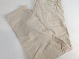 un pantalon beige posé sur un lit recouvert d'un drap blanc