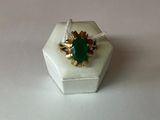 une bague sertie d'une pierre verte, posée sur une boîte blanche