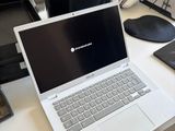 a laptop computer sitting on a desk next to a chair