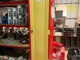un casier rouge et jaune dans un garage où se trouvent de nombreux autres objets