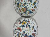 two plates with floral designs on them sitting on a table