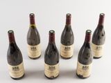 six bottles of wine are lined up in a row on a white surface