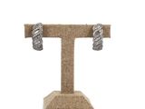pair of silver tone earrings on a burlocked stand