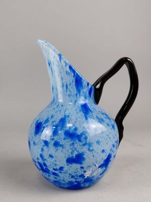 un pichet en verre bleu et noir muni d'une anse noire