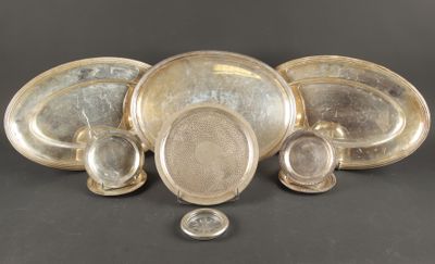 Plusieurs assiettes et bols en argent sont disposés sur une surface noire