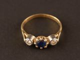 gros plan d'une bague en or avec un saphir et des diamants