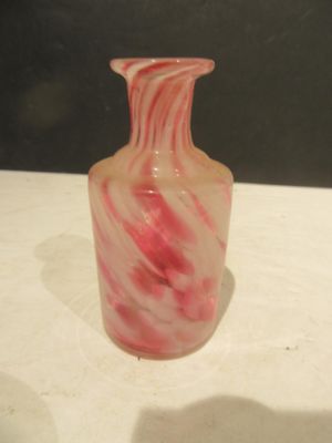 a pink and white vase sitting on a white table