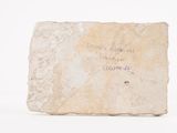 an old stone block with writing on it sitting on a white surface