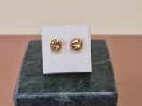 a pair of gold stud earrings sitting on top of a white square