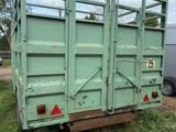 a green trailer that is sitting in the grass