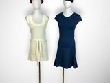 two mannequins with hats and dresses on display on a gold stand