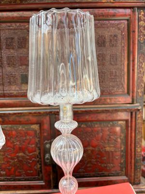 une lampe en verre posée sur une table, à côté d'un livre rouge