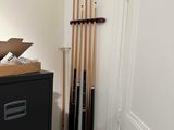 a black filing cabinet in the corner of a room with a bunch of pool cues on top of it