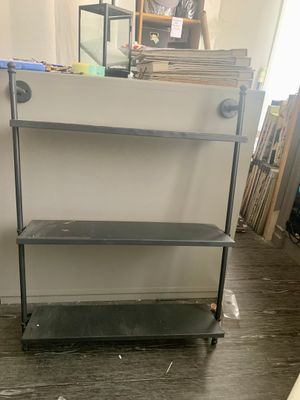 une étagère métallique comportant deux tablettes, dans une pièce