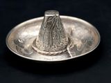 a silver plate with a silver hat on top of it