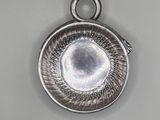 silver plated pendant with a circular design on the front of it