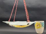 a ceramic hanging planter with a painting of a boat on it