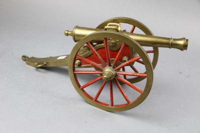 a red and gold cannon sitting on a white surface