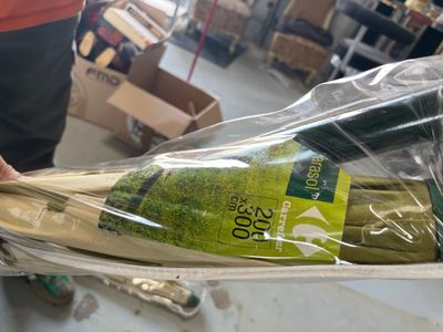 une personne tenant une bouteille de vin emballée dans du plastique