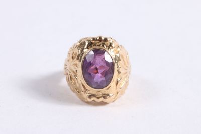gros plan d'une bague en or avec une pierre violette