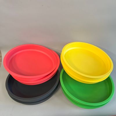 quatre assiettes de couleurs différentes posées sur une table blanche