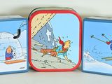three tins with pictures of people skiing on them