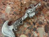 une tête de dragon en argent au sommet d'une hache en argent