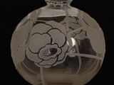 un vase en verre orné d'une fleur, posé sur un socle en bois