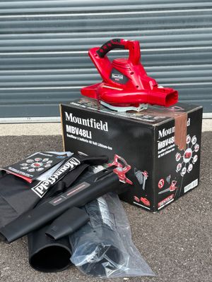 un ventilateur rouge posé sur une boîte, à côté d'un parapluie noir