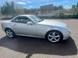 une Mercedes SLK argentée garée sur un parking, près d'une clôture