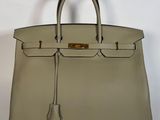 un sac à main en cuir blanc avec des finitions dorées sur la poignée