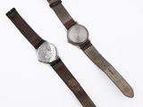 two watches sitting on top of each other on a white surface