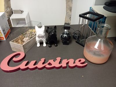 une table sur laquelle se trouvent un vase, une bouteille et une figurine de chat