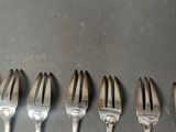 six forks are lined up in a row on a table