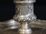 an antique silver plate with a silver cup on top of it