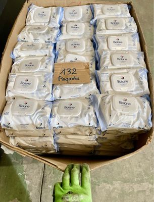 une boîte en carton remplie de paquets de savon et une main tenant un gant vert
