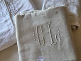 trois serviettes de table en lin blanc ornées de monogrammes brodés