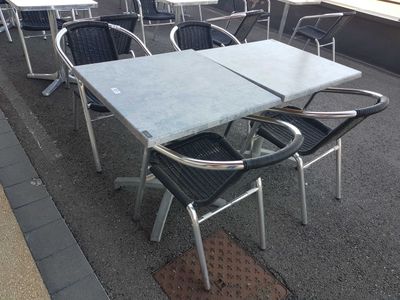 many chairs and tables on the sidewalk outside of a restaurant